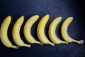 Unusual and fresh photo of bananas lying in a row on black background. Stylish