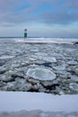 Icebergs drifting in icy water with lighthouse in background