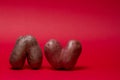 Unusual shaped vegetables. Two ugly heart-shaped potatoes on a red background. Copy space Royalty Free Stock Photo