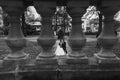 Unusual view through columns at gorgeous bride and stylish groom walking at old castle in european park in autumn time. happy Royalty Free Stock Photo