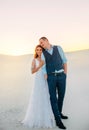 Unusual wedding photo shoot in the desert. Background white sands at sunset. Happy brunette girl with long hair hugging Royalty Free Stock Photo