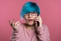 Unusual woman with blue hair making call with smartphone over pink wall Royalty Free Stock Photo