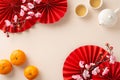 Top view scene: fans, teapot, cups with green tea cherished family ritual. Tangerines, sakura, and pastel beige space Royalty Free Stock Photo