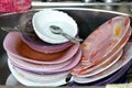 Unwashed kitchen utensils in the wash basin need to be cleaned and washed, a pile of dirty dishes, knives, pots and drinking glass Royalty Free Stock Photo