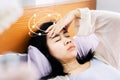 Unwell Asian woman suffering from dizziness after wakeup in morning hand holding her head lying down in bed Royalty Free Stock Photo