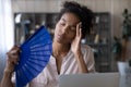 Unwell biracial woman wave with hand fan working on computer Royalty Free Stock Photo
