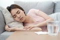 Unwell condition young Asian girl sleeping on sofa after checking temperature and taking medicines and water, Health and illness Royalty Free Stock Photo