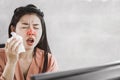 Unwell female Asian having flu and cold sneezing at work place Royalty Free Stock Photo