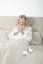 Unwell senior woman blowing nose in bed