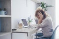 Unwell young Caucasian woman work on computer at home office take off glasses suffer from migraine or headache. Unhappy tired Royalty Free Stock Photo