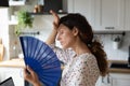 Unwell young woman feel overheated using hand fan