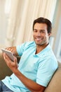 Unwinding at home with his tablet. Portrait of a handsome man using a digital tablet while sitting on the sofa at home. Royalty Free Stock Photo