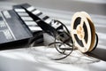 Unwound narrow retro film strip on a light reel with a movie clapperboard Royalty Free Stock Photo