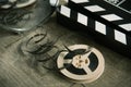 Unwound narrow retro film strip on a light reel with a movie clapperboard on a wooden table background Royalty Free Stock Photo