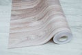 Unwound roll of beige linoleum with wood texture on white wooden floor