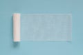 Unwound roll of white sterile medical bandage for dressing wounds on a blue background, copy space Royalty Free Stock Photo