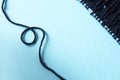 Unwound thread. Knitting black yarn and a ball of thread and knitting needles on blue background Royalty Free Stock Photo