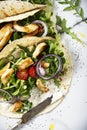 Unwrapped tortilla with fresh salad and roasted chicken and a bowl of sauce.