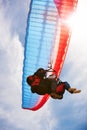 Up and away. View from directly below two people doing tandem paragliding with the sun and sky in the background. Royalty Free Stock Photo