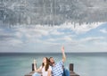 up side down city in the sky over the sea with couple sit on a dock and looking up Royalty Free Stock Photo