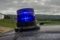 Up view of close-up of a blue police flashing light on on the roof of the car