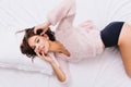 Up view relaxed attractive young bikini model in woolen pink sweater on bed. Amazing charming girl waking up, enjoying