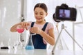 Upbeat girl pouring chemicals and recording vlog