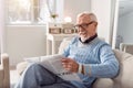 Upbeat senior man smiling while reading article in newspaper Royalty Free Stock Photo