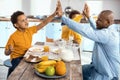 Upbeat single-parent family high-fiving each other at breakfast