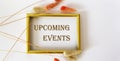 Upcoming event message on a gold frame with dry flowers