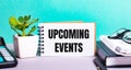 UPCOMING EVENTS is written on a white card next to a potted flower, diaries and calculator. Organizational concept Royalty Free Stock Photo