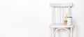 Upcycling concept. Repainting an retro chair. Old white wooden chair against white wall. Banner format