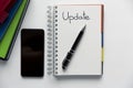 Update - handwritten text in a notebook on a desk. Project update checklist. Notebook, pen and books