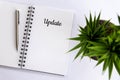 UPDATE. Single creative word on a notepaper book. With pen and green plant on white table background. Royalty Free Stock Photo