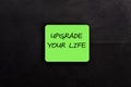upgrade your life text on green sticker over black background. Royalty Free Stock Photo