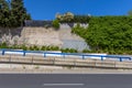 An uphill urban street with a blue metal railing and a wall largely