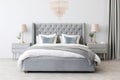 Upholstered bed in a luxurious bedroom in soft blue and gray tones