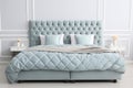 Upholstered bed in a luxurious bedroom in soft blue and gray tones