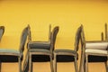 Upholstered chairs stacked against a bright yellow concrete block wall