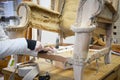 Upholsterer stretching new straps on old wooden chair construction.