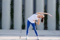 Uplifted woman stretching on a concrete paving, doing side bends