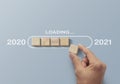 2021 uploading, reboot, refresh or mindset concept. Hand putting wooden blocks in progress bar on gray background with the word Royalty Free Stock Photo
