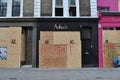 Upmarket boutiques boarded up covered graffiti