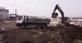 Upper aerial shot: a tractor bucket fills the truck body. An excavator and a truck load the ground. Flight over the
