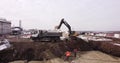 Upper aerial shot: a tractor bucket fills the truck body. An excavator and a truck load the ground. Flight over the