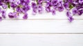 Upper border of beautiful small lilac flowers on wooden white background, copy space