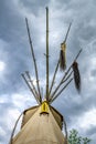 Upper end of an Indian teepee with poles, ponytail and yellow pearl decoration