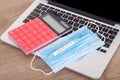 Upper face mask, mercury thermometer and calculator on laptop keyboard Royalty Free Stock Photo