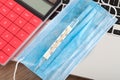 Upper face mask, mercury thermometer and calculator on laptop keyboard Royalty Free Stock Photo