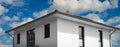 Upper floor of a modern minimalist house, blue sky with clouds in the background, view from public ground Royalty Free Stock Photo